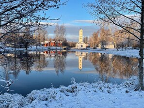 A serene winter scene with a calm lake reflecting buildings and trees. - Romantic Spa Villa With Fireplace by the Lake (Stjärnsund)