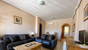 A living room with a black sofa, wooden coffee table, and a TV on a wooden stand.