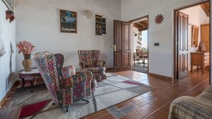 Un salon avec des fauteuils à motifs, une table basse et un tapis.