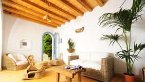 A cozy living room with wicker furniture, a white sofa, and a large potted plant.