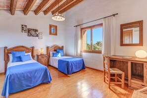 Un dormitorio con dos camas, muebles de madera, un escritorio y una ventana con cortinas.