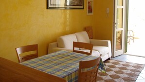 A room with a dining table, chairs, a sofa, and a patterned rug. - Ammiraglia Residence just 200 meters from the beaches - Villa A (Baia Verde)