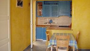 A kitchen with blue cabinets, a dining table with a plaid tablecloth, and chairs. - Ammiraglia Residence just 200 meters from the beaches - Villa A (Baia Verde)