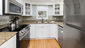 Una cocina moderna con armarios blancos, un refrigerador de acero inoxidable, un microondas y una estufa.