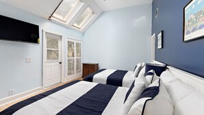 Un dormitorio con dos camas, un tragaluz, una puerta y una ventana.