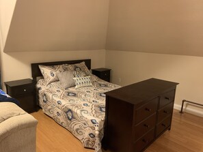 A bedroom with a bed, nightstands, a dresser, and a chair.