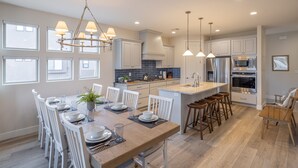 A modern kitchen with a central island, white cabinetry, and pendant lighting. - Red Rock Views - 3 King En Suites + Rooftop Patio (St. George)