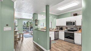 A modern kitchen with white cabinets, stainless steel appliances, and a wooden floor. - Destin West G204 — Gulfside 2BR + Bunk Room, Sleeps 8 (Fort Walton Beach)