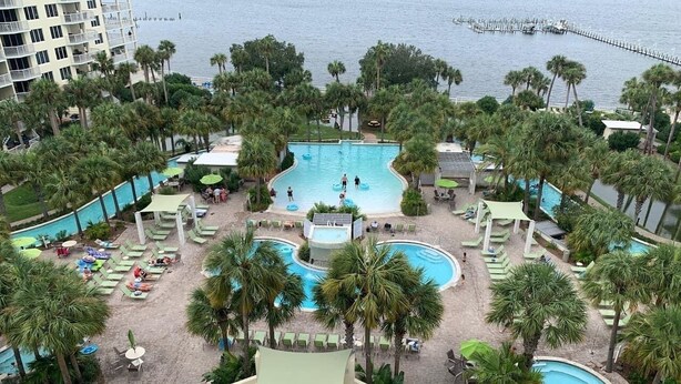 A resort with multiple swimming pools surrounded by palm trees and lounge areas. - Destin West G204 — Gulfside 2BR + Bunk Room, Sleeps 8 (Fort Walton Beach)