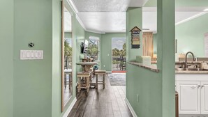 A hallway with a kitchen area, wooden furniture, and a view of the outdoors. - Destin West G204 — Gulfside 2BR + Bunk Room, Sleeps 8 (Fort Walton Beach)