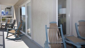 Un balcon avec des fauteuils à bascule, une porte vitrée et une vue sur l’intérieur du bâtiment.