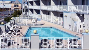 Un hôtel à plusieurs étages doté d’un espace piscine sur le toit, comprenant des chaises longues et une piscine.
