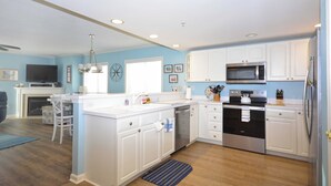 Une cuisine moderne avec des armoires blanches, des appareils en acier inoxydable et un mur d’accent bleu.