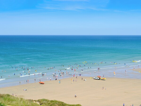 A beach with people, kayaks, and a lifeguard tower.