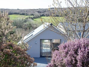 A modern house with a sloped roof, a glass door entrance, and a view of the surrounding landscape. - 1 bedroom accommodation in Perranporth (Perranporth)