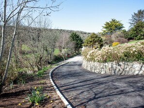 A winding road with a stone wall on one side and trees on the other.