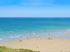 A beach with people, a lifeguard tower, and a clear sky. - 1 bedroom accommodation in Perranporth (Perranporth)