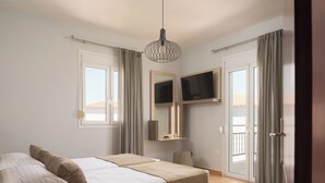 Une chambre avec un lit, un téléviseur fixé au mur et une porte-fenêtre coulissante donnant sur un balcon extérieur.