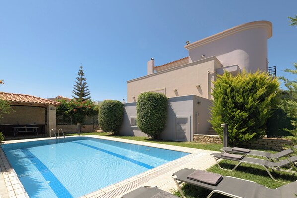 Een buitenzwembad, ligstoelen bij het zwembad