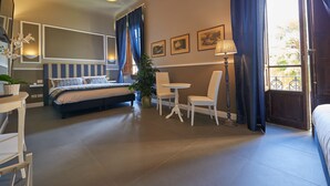 A hotel room with a bed, bedside table, lamp, chairs, and a small table. - Large private room in historycal building (Firenze)