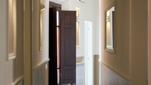 A narrow hallway with a door at the end, a radiator, and a mirror on the wall. - Large private room in historycal building (Firenze)