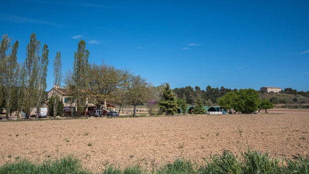 A rural landscape with a dirt field, a few trees, and a building in the background. - Le Grand Galla, country apartment (PERTUIS)