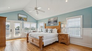 A bedroom with a large bed, wooden floor, white walls, and a ceiling fan. - 8BR Beach Oasis w/ Pool & Rooftop (Isle of Palms)
