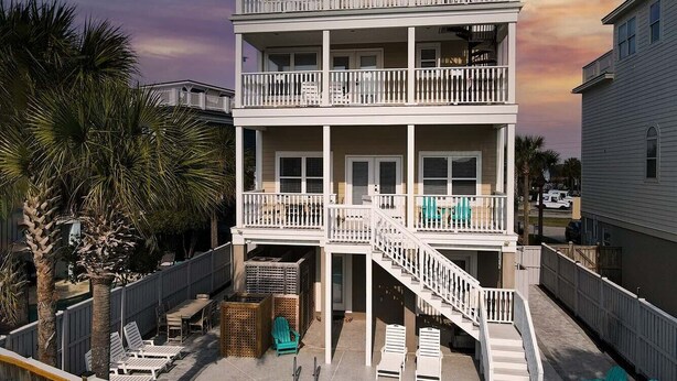 A two-story building with a balcony, a pool, and outdoor seating. - 8BR Beach Oasis w/ Pool & Rooftop (Isle of Palms)