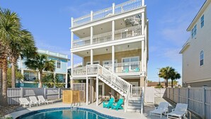 A two-story building with a pool, outdoor seating, and a staircase leading to the upper floor. - 8BR Beach Oasis w/ Pool & Rooftop (Isle of Palms)