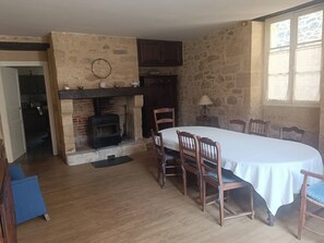 Un coin repas agrémenté d’une cheminée en pierre, de chaises en bois et d’une table dressée pour quatre personnes.