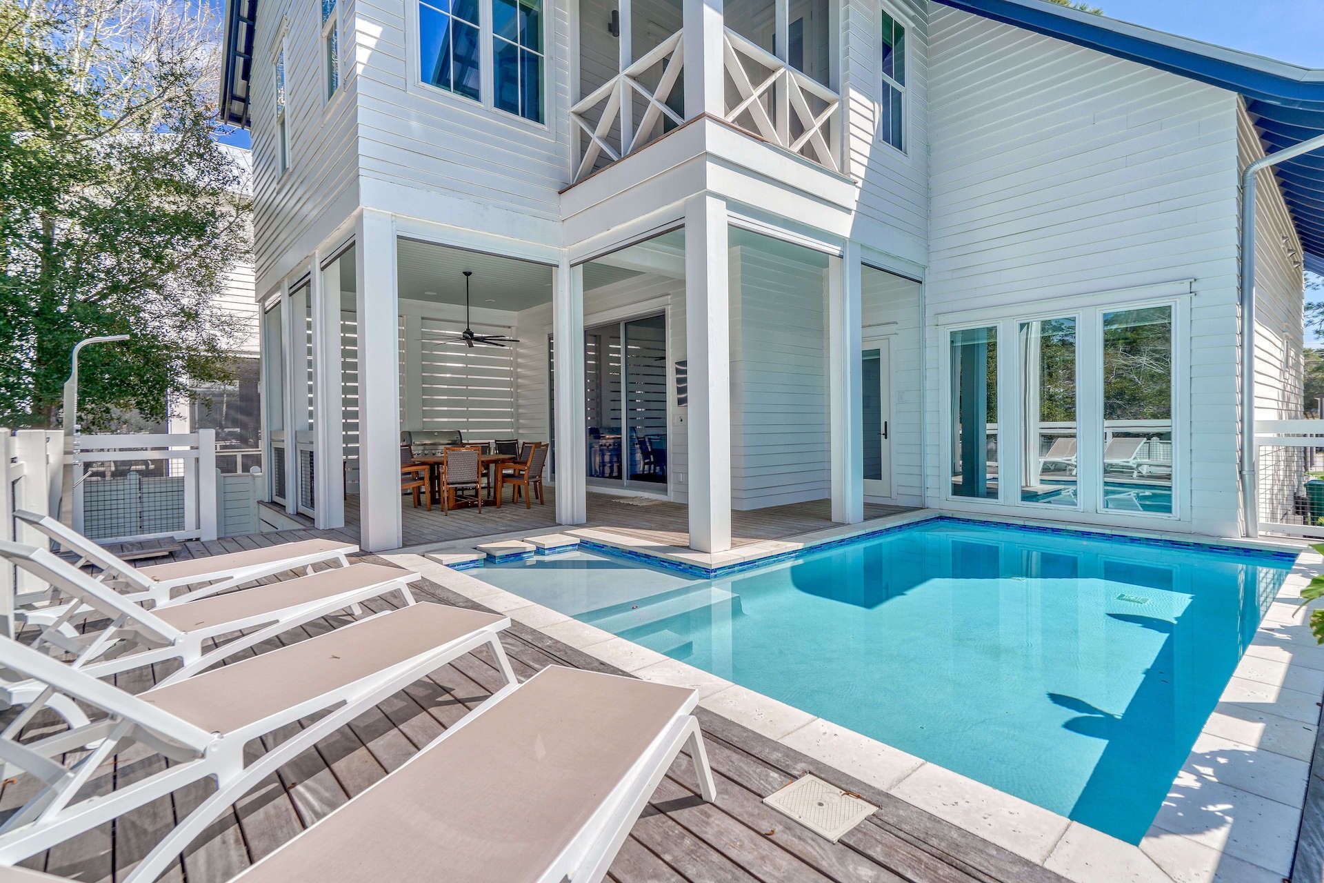 A two-story house with a swimming pool, outdoor furniture, and a covered patio area.
