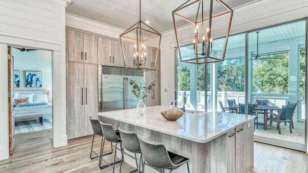 A modern kitchen with a central island, bar stools, and pendant lighting. - Luxury Home 1 Minute to the Gulf, with LSV, Bikes, and Heated Pool (Santa Rosa Beach)