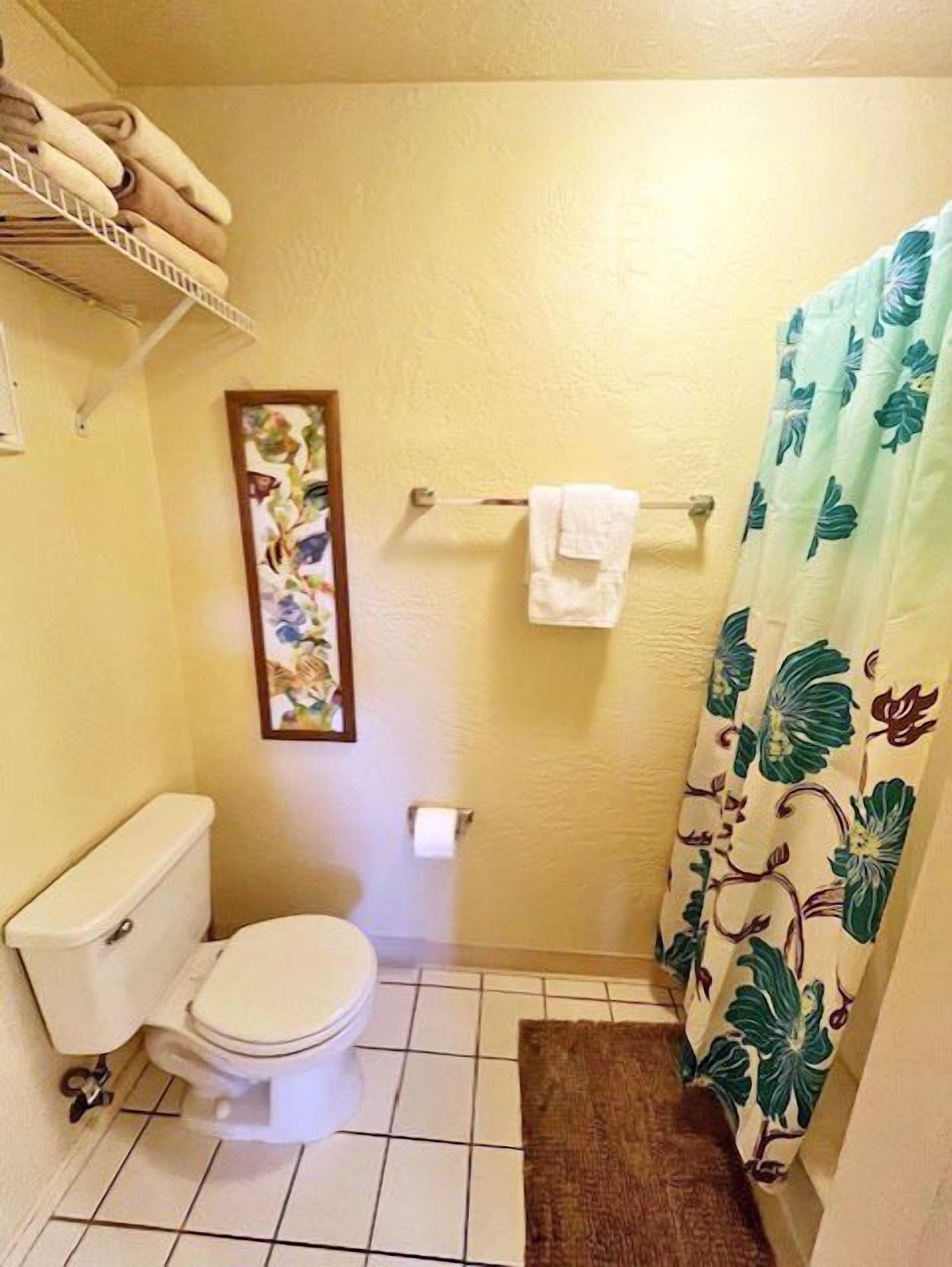 A small bathroom with a toilet, a shower curtain, and a towel rack.