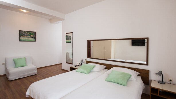 Une chambre d’hôtel avec un grand lit, un canapé, un miroir et une télévision.