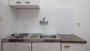Une cuisine équipée d’une cuisinière, d’un évier et de meubles blancs.