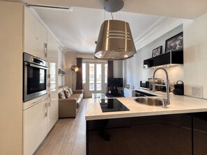 Une cuisine moderne dotée d’un îlot central, d’un four encastré et d’un coin repas avec un canapé.