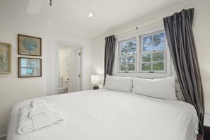 A hotel room with a large bed, a window with curtains, and two framed pictures on the wall. - Redbird Beach: 7BR Beachfront Home- Priv. Pool, Pet Friendly, Sleeps 23! (Port St Joe)
