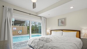 A bedroom with a large bed, a view of a swimming pool, and a sliding glass door. - Redbird Beach: 7BR Beachfront Home- Priv. Pool, Pet Friendly, Sleeps 23! (Port St Joe)