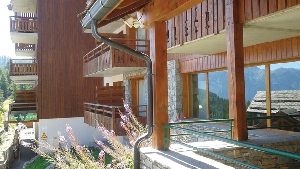 Un edificio de madera con balcones, paredes de piedra y amplias ventanas que ofrecen vistas a las montañas.