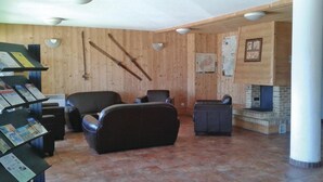Un vestíbulo con paredes de madera, chimenea, asientos de cuero y paneles informativos.