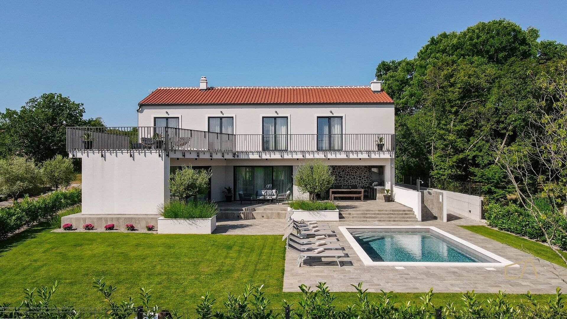 Une maison à deux étages avec une piscine, un patio couvert et un mur en pierre.