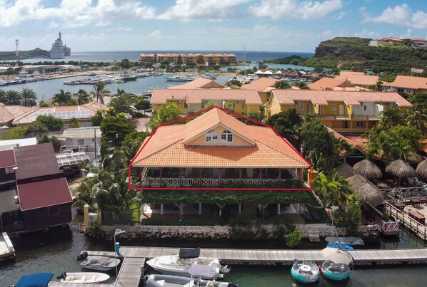 Ein Küstenhotel mit einem Gebäude mit rotem Dach, einer Marina voller Boote und Blick auf das Meer und einen Leuchtturm.