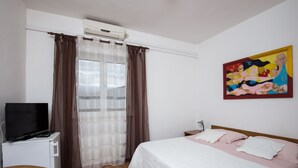 A hotel room with a bed, a TV, a desk, and a painting on the wall. - Villa Konalić - Double or Twin Room with Balcony and Sea View 1 (Mokosica)