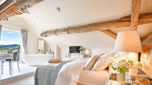 Un dormitorio con una cama grande, una bañera, un televisor y vistas al exterior.