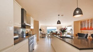 Una cocina moderna con una isla central, electrodomésticos de acero inoxidable e iluminación colgante.