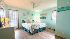 A bedroom with a bed, a ceiling fan, a nightstand, a dresser, and a door with blinds. - N3325-Oceanside, Nags Head, Saturday Check In, Private Pool! (Nags Head)
