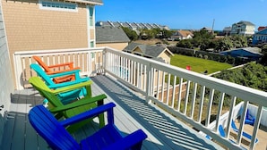 A wooden deck with colorful Adirondack chairs and a view of a residential area. - N3325-Oceanside, Nags Head, Saturday Check In, Private Pool! (Nags Head)