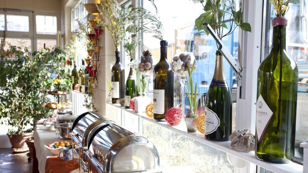 A buffet setup with a variety of food items and a wine selection displayed on shelves. - Hotel Henry (Erding)