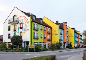 Una hilera de edificios hoteleros coloridos con balcones, un letrero que indica un restaurante y un cielo despejado.
