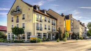 A hotel with a yellow facade, multiple balconies with flower boxes, and a sign indicating 'Hotel Henry'. - Hotel Henry (Erding)